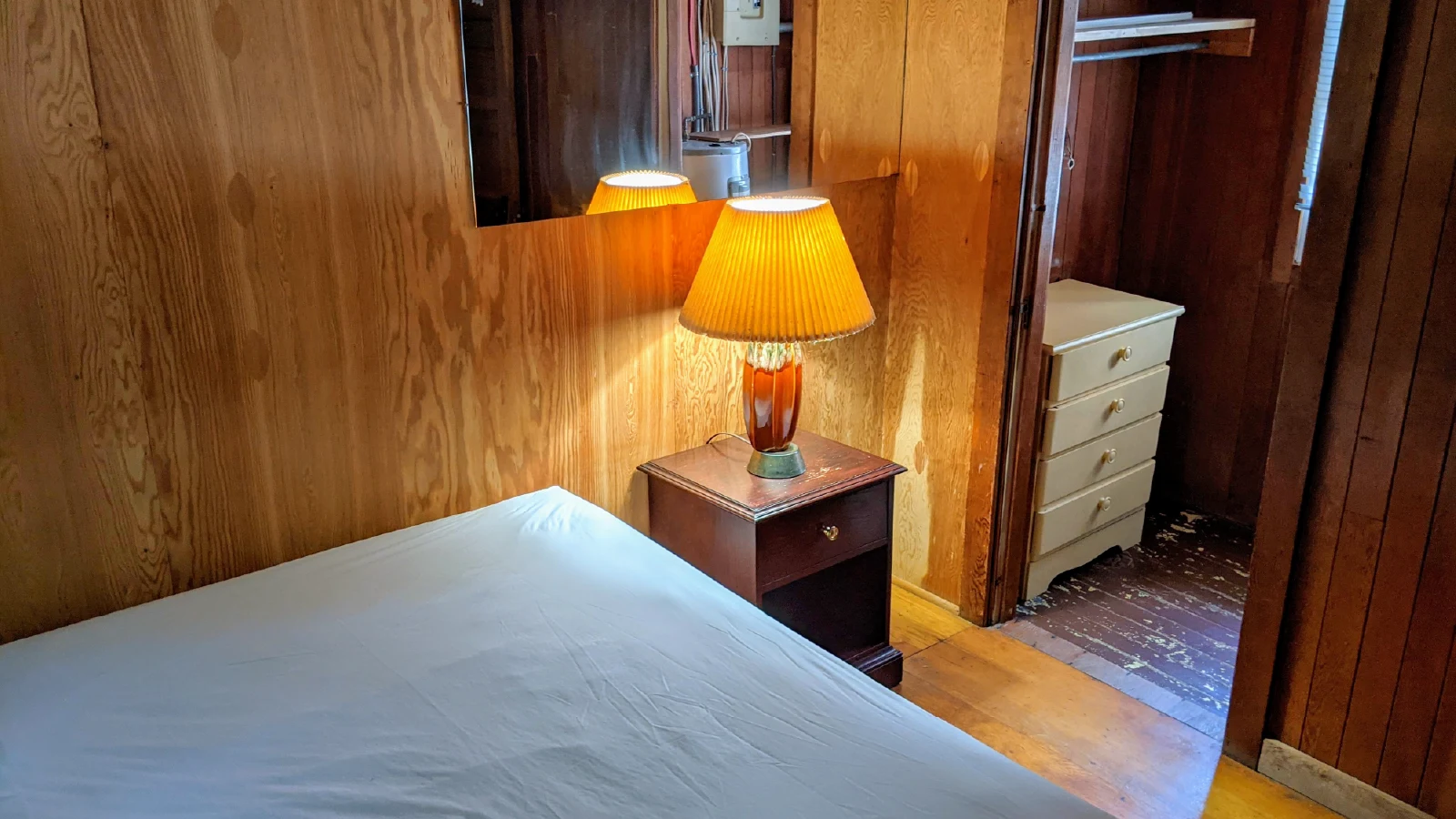 Pigeon Lake Resort Cottage Six, second bedroom with bed, bedside table and lamp, mirror, and open closet with dresser.